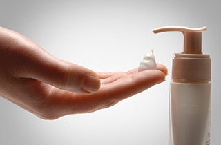 Open hand showing the use of a cream from a pump bottle, visual illustrating the "Consuming sustainably" pillar of the programme "Sharing Beauty With All".